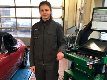 Azubi neben Auto in Werkstatt