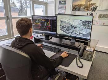 Mitarbeiter am Rechner mit Konstruktionszeichnung